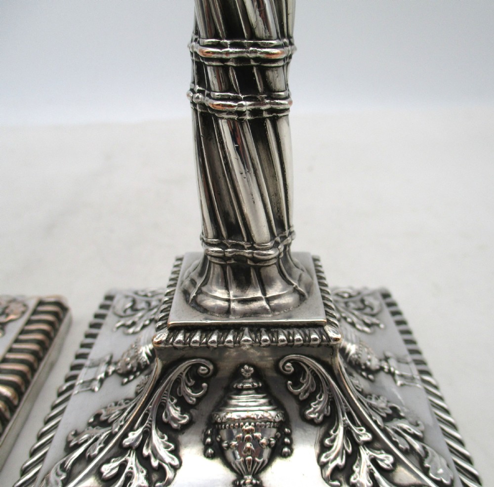 A pair of silver-plated taper candlesticks featuring spiral-fluted columns, foliage capitals, and decorative square bases. View XII