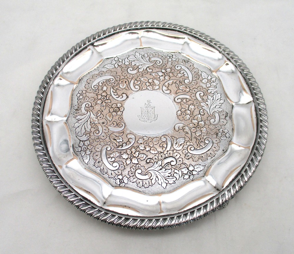 A circular Regency period Old Sheffield plated card tray featuring an engraved floral surface, armorial crest centre, pie-crust rim, and rope-twist border. View II