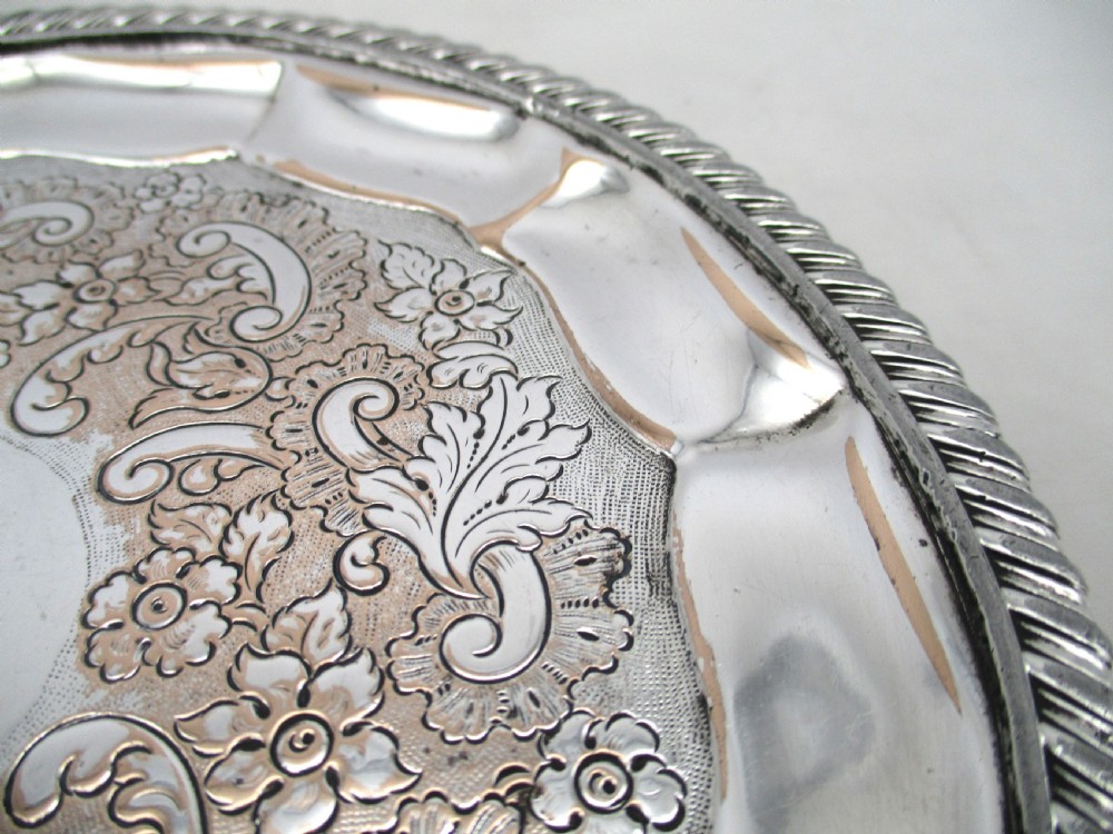 A circular Regency period Old Sheffield plated card tray featuring an engraved floral surface, armorial crest centre, pie-crust rim, and rope-twist border. View V