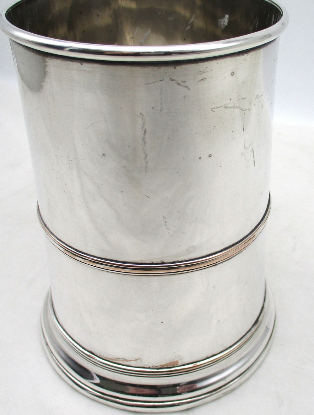 A Georgian Old Sheffield silver-plated quart tankard featuring a tapered body with a central girdle, moulded foot, and C-scroll handle. View VI