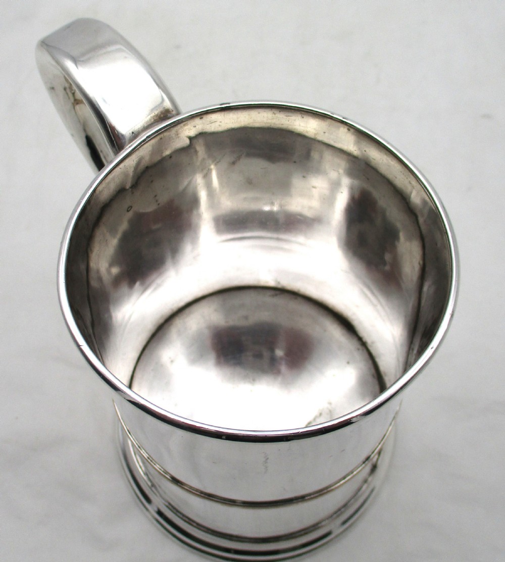 A Georgian Old Sheffield silver-plated quart tankard featuring a tapered body with a central girdle, moulded foot, and C-scroll handle. View VII
