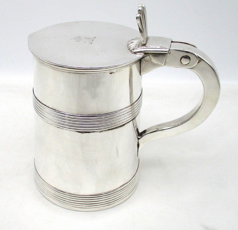 A silver-plated lidded tankard featuring a hinged lid with a thumbpiece, horizontal reeded banding, and a glass base.