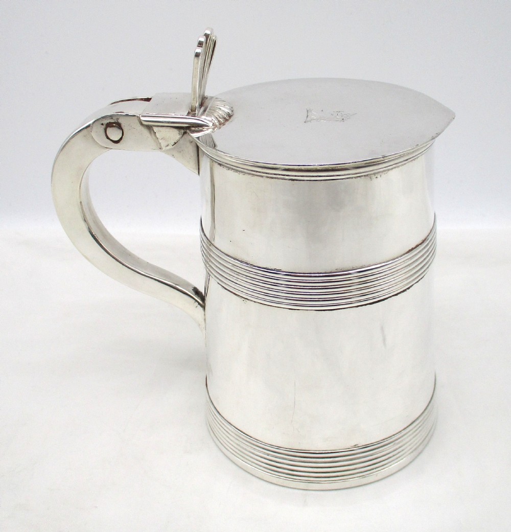 A silver-plated lidded tankard featuring a hinged lid with a thumbpiece, horizontal reeded banding, and a glass base. View V