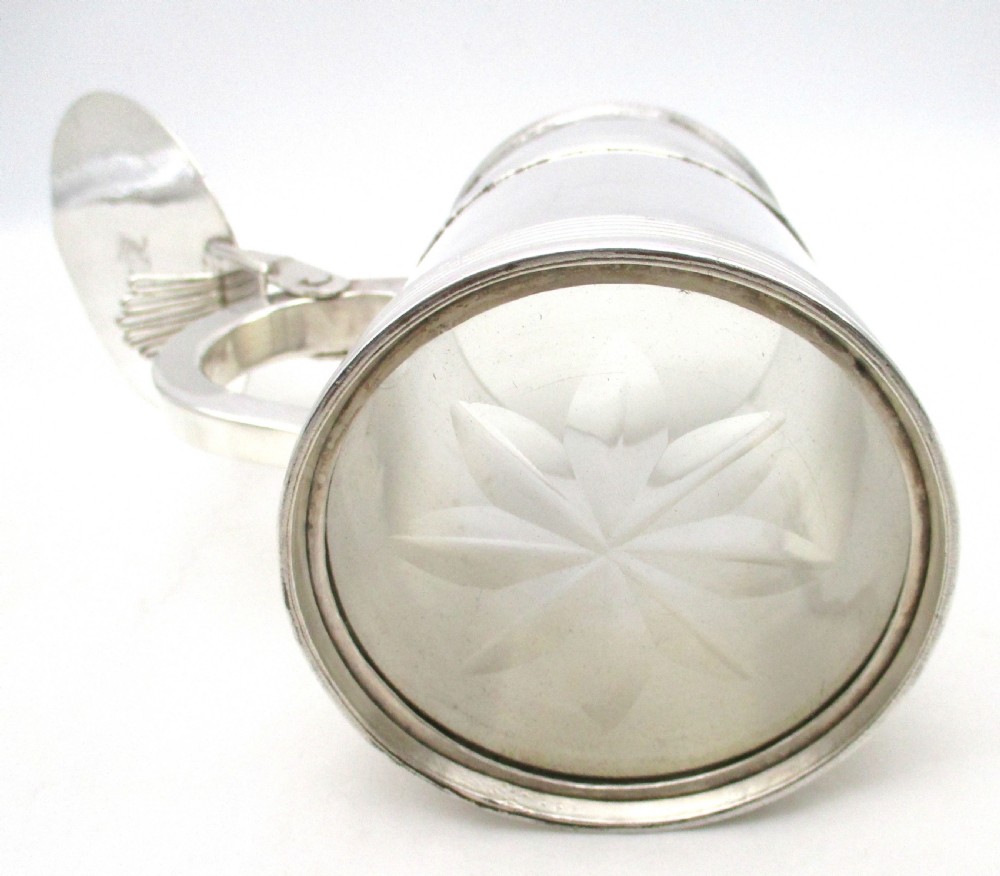 A silver-plated lidded tankard featuring a hinged lid with a thumbpiece, horizontal reeded banding, and a glass base. View VIII