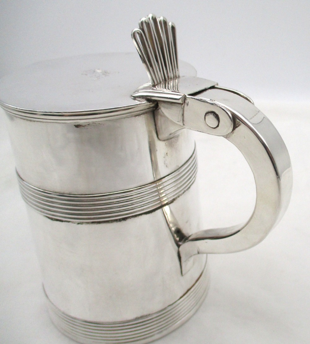 A silver-plated lidded tankard featuring a hinged lid with a thumbpiece, horizontal reeded banding, and a glass base. View IX