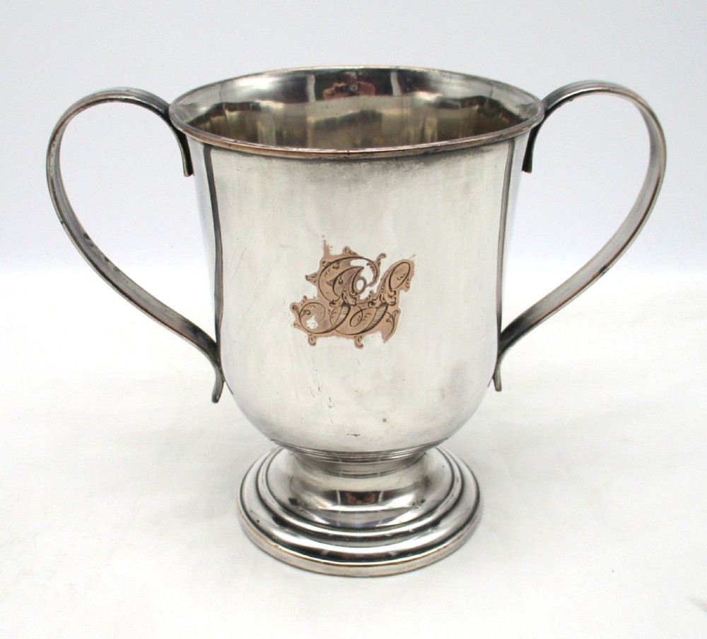 A Georgian silver-plated two-handled cup featuring a flared pedestal foot, looped side handles, and a central engraved crest. View III