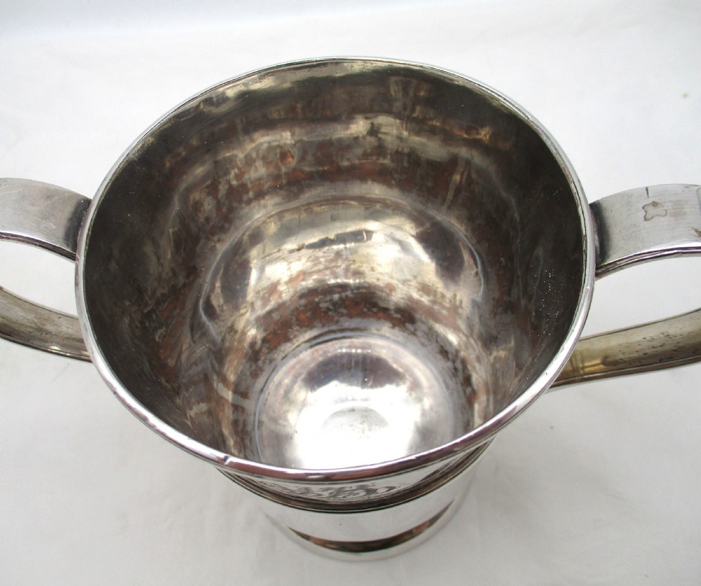 An antique silver-plated two-handled loving cup featuring a central girdle band, moulded foot, and an engraved monogram. View VII