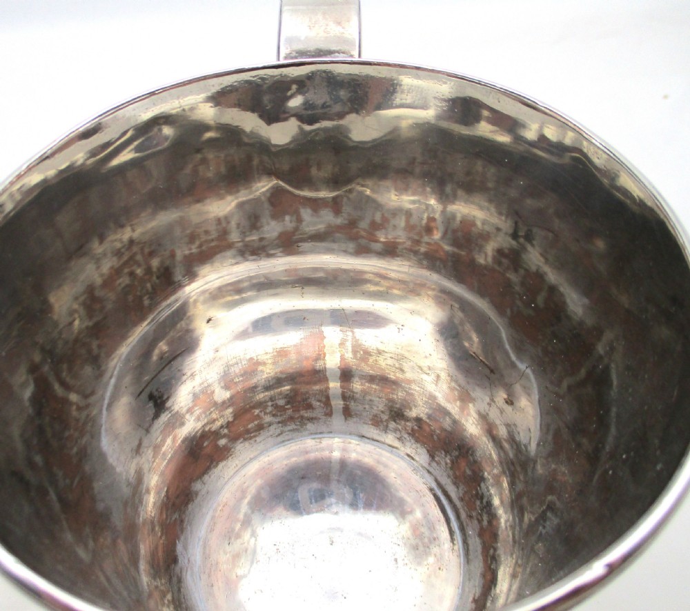 An antique silver-plated two-handled loving cup featuring a central girdle band, moulded foot, and an engraved monogram. View VIII