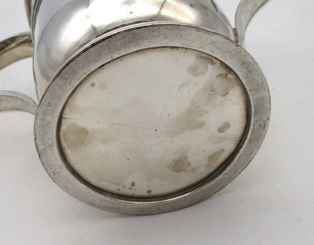 An antique silver-plated two-handled loving cup featuring a central girdle band, moulded foot, and an engraved monogram. View X