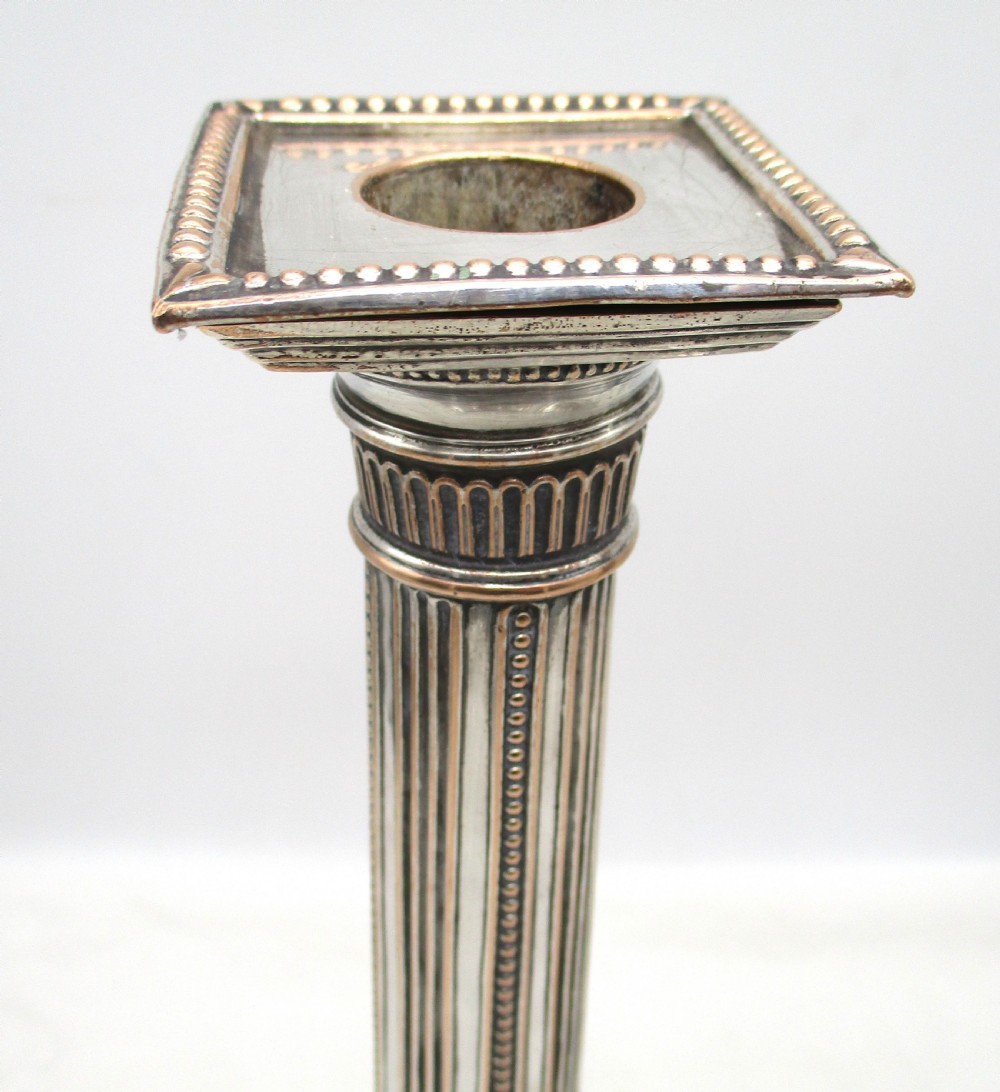 A pair of 18th-century Old Sheffield plated silver candlesticks featuring fluted columns, beaded square bases, and square nozzles. View IV