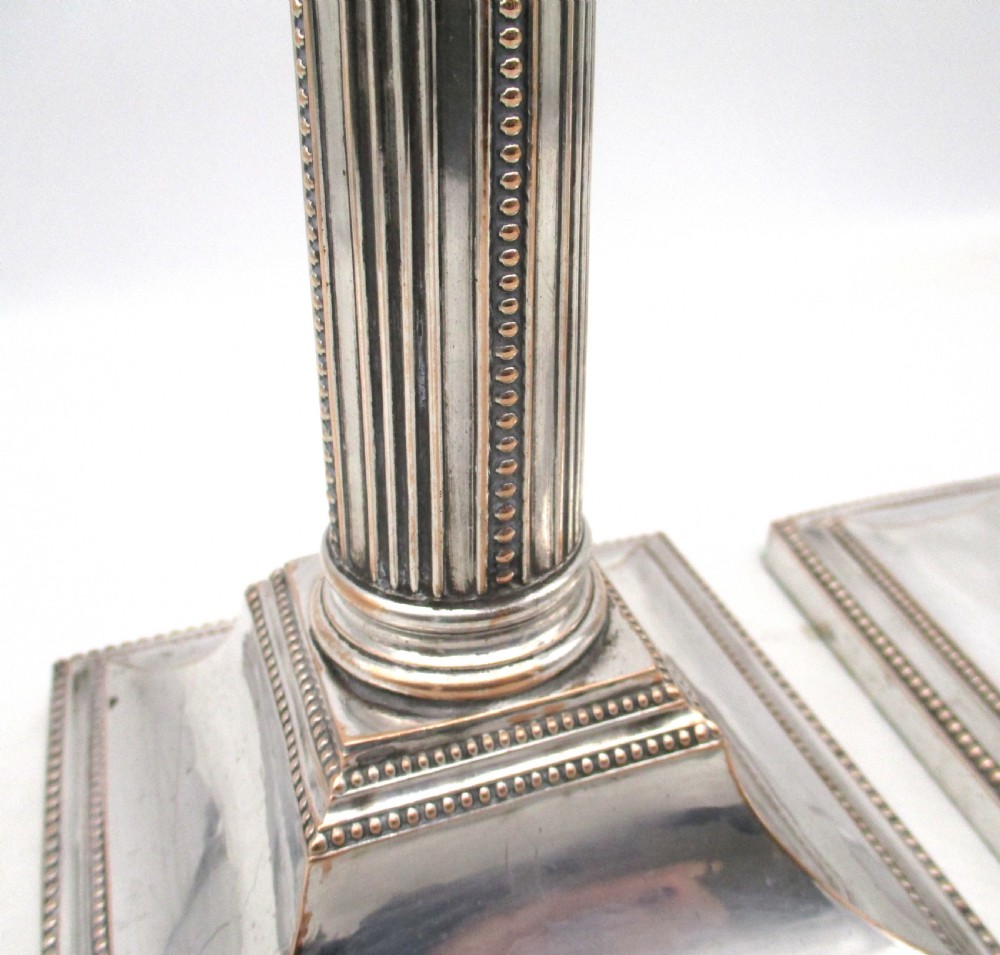 A pair of 18th-century Old Sheffield plated silver candlesticks featuring fluted columns, beaded square bases, and square nozzles. View VI