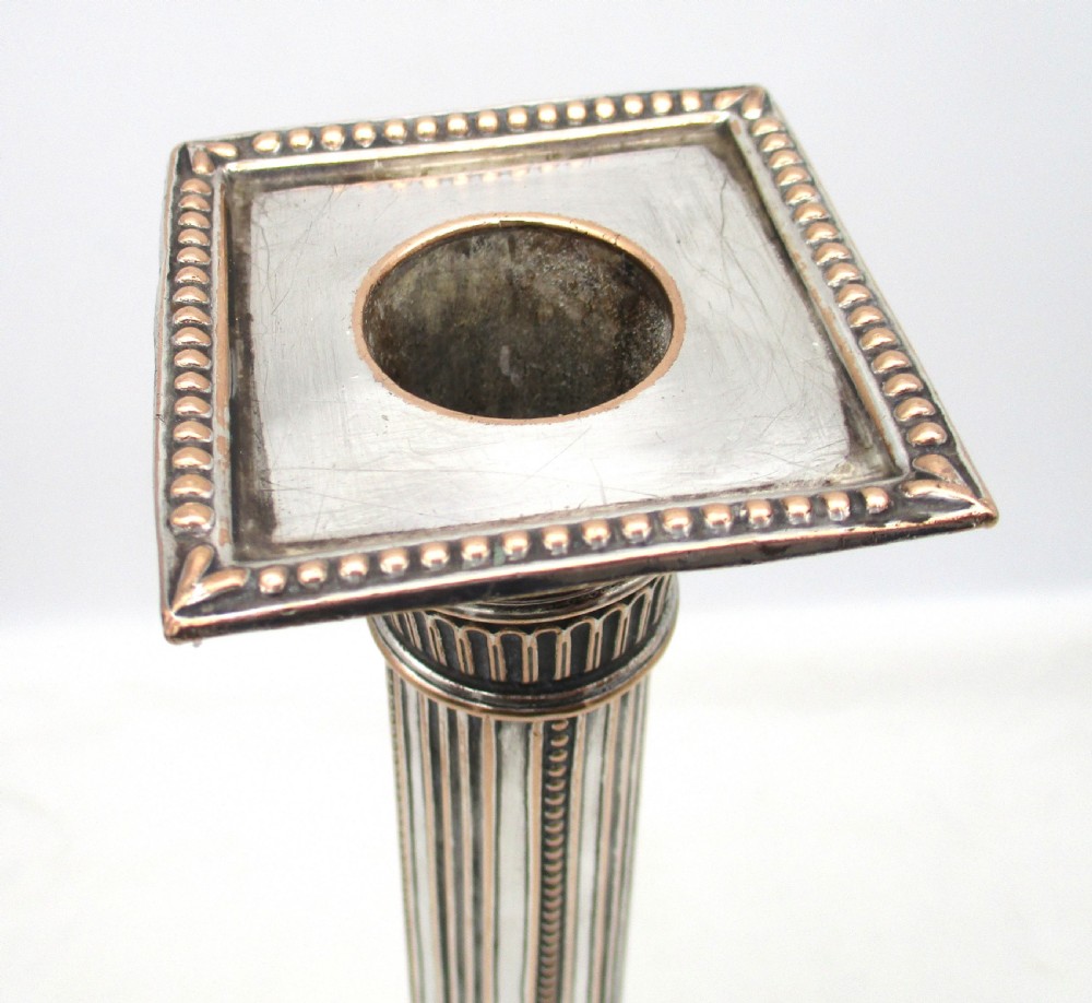 A pair of 18th-century Old Sheffield plated silver candlesticks featuring fluted columns, beaded square bases, and square nozzles. View VII