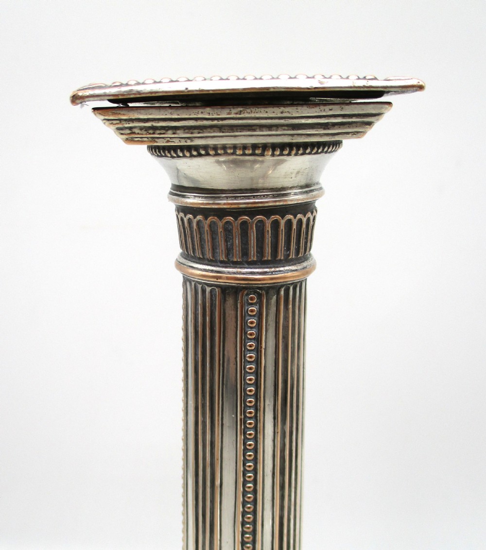 A pair of 18th-century Old Sheffield plated silver candlesticks featuring fluted columns, beaded square bases, and square nozzles. View IX
