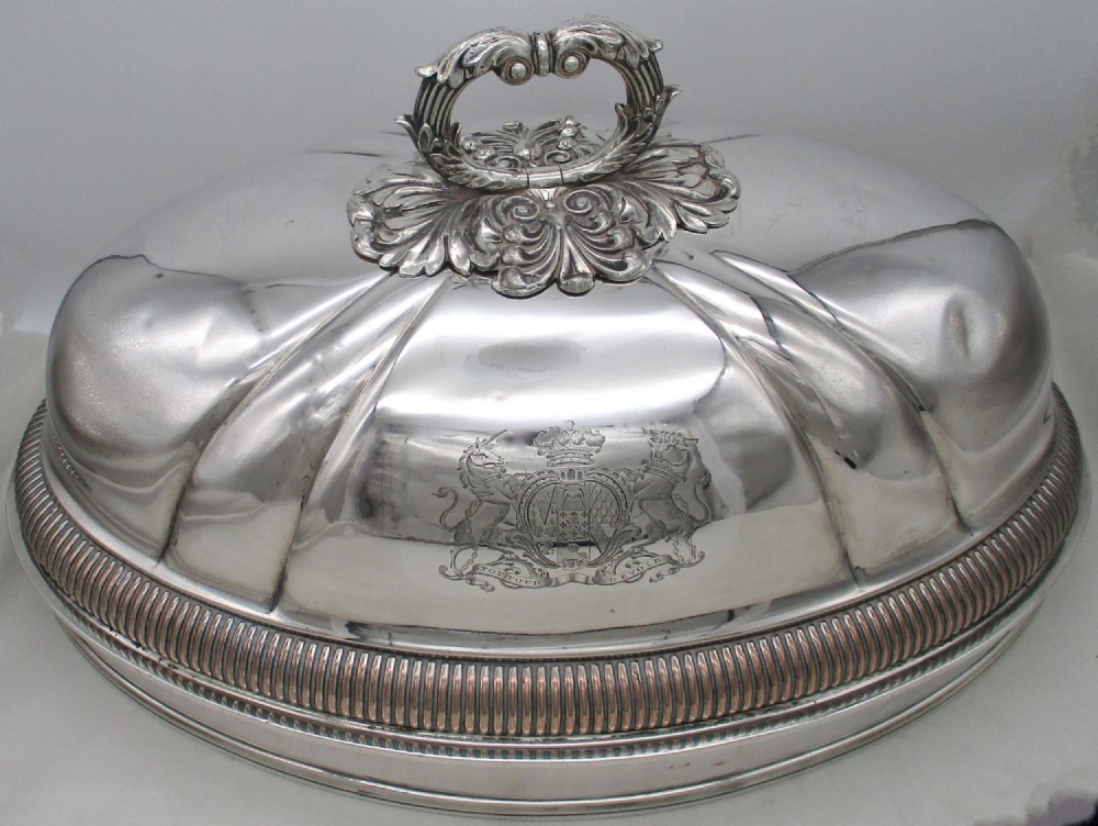 An oval Regency era Old Sheffield Plate domed meat cover featuring a decorative cast handle, engraved coat of arms, and gadrooned border.