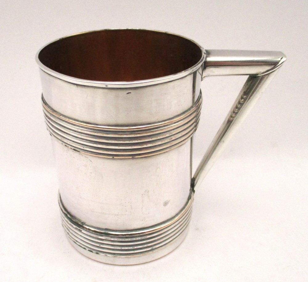 A pair of cylindrical silver-plated tankards featuring horizontal reeded bands, angular handles, and gilded interiors. View II