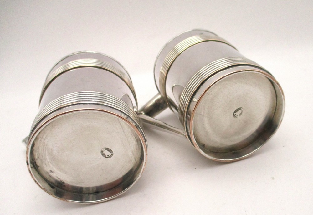 A pair of cylindrical silver-plated tankards featuring horizontal reeded bands, angular handles, and gilded interiors. View IV