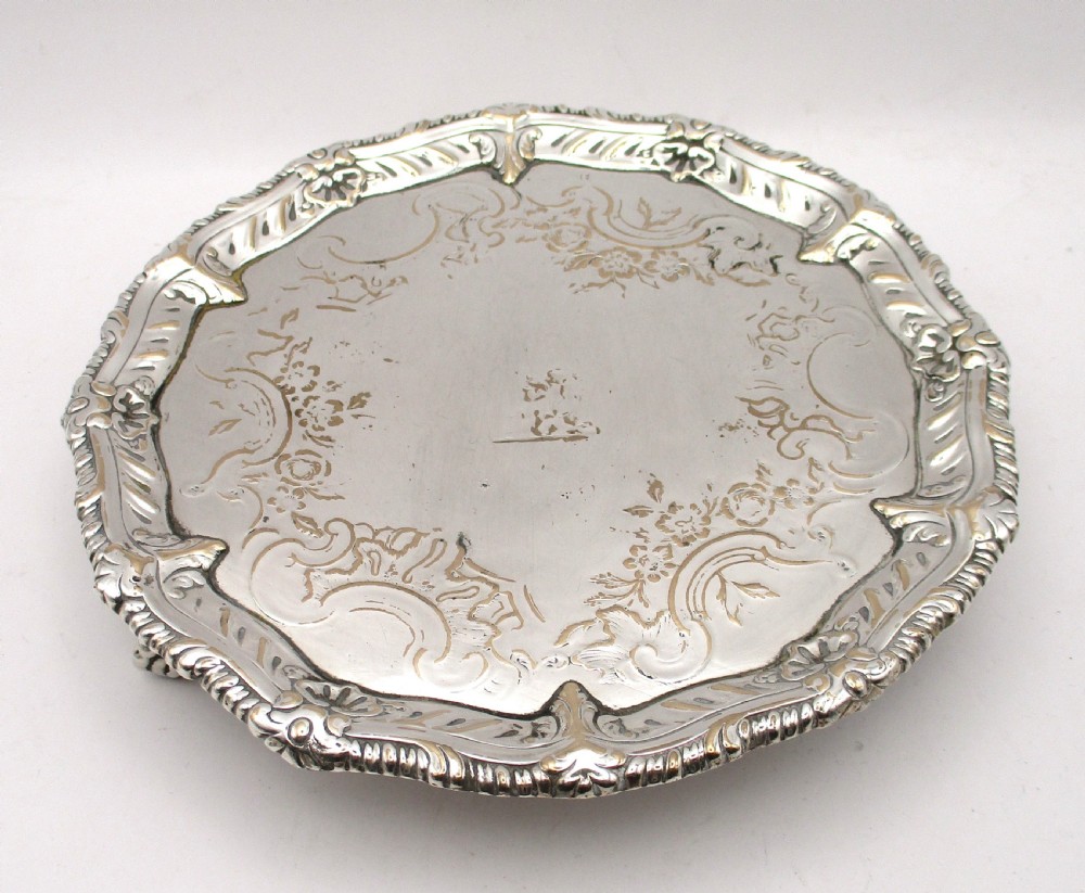 A circular Georgian Old Sheffield plated card waiter with a scalloped chased rim and etched floral scroll motifs on the surface.