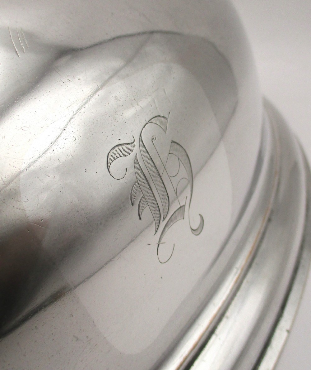 An oval domed silver-plated food cover featuring a cast leaf motif top handle and an engraved crest on the front. View III