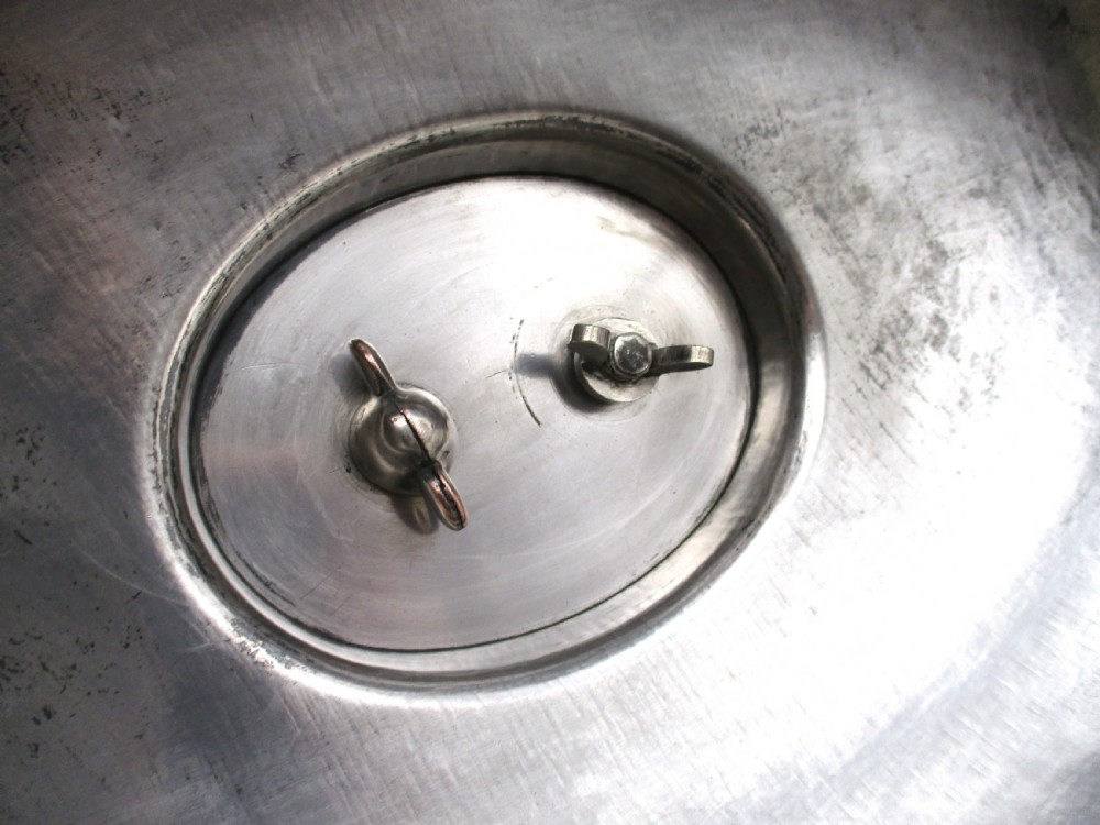 An oval domed silver-plated food cover featuring a cast leaf motif top handle and an engraved crest on the front. View V