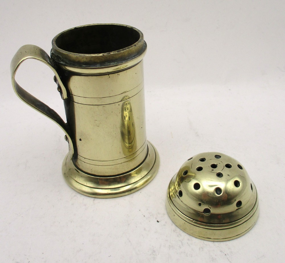 An eighteenth-century brass spice dredger featuring a perforated domed lid, a cylindrical body with moulded bands, a curved strap handle, and a stepped circular base. View IX