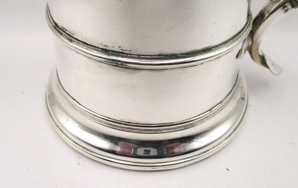 An 18th-century silver-plated beer jug with a domed hinged lid, thumbpiece, spout, and curved scroll handle. View IV
