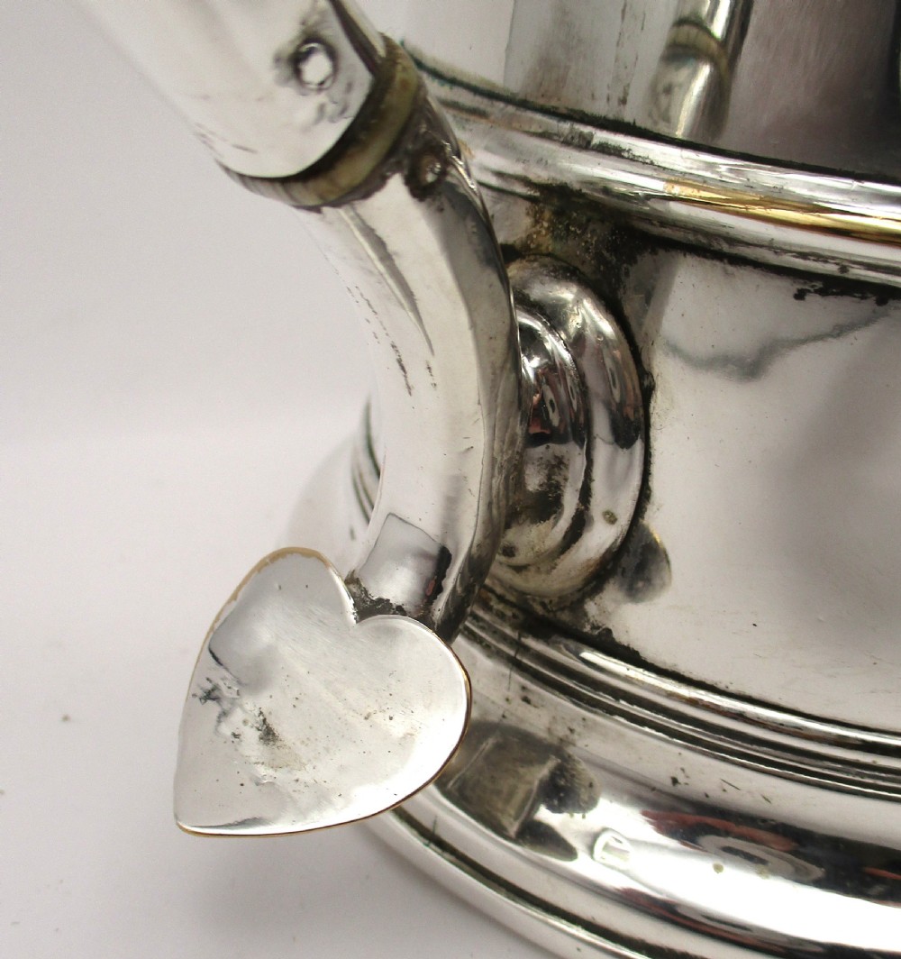 An 18th-century silver-plated beer jug with a domed hinged lid, thumbpiece, spout, and curved scroll handle. View V