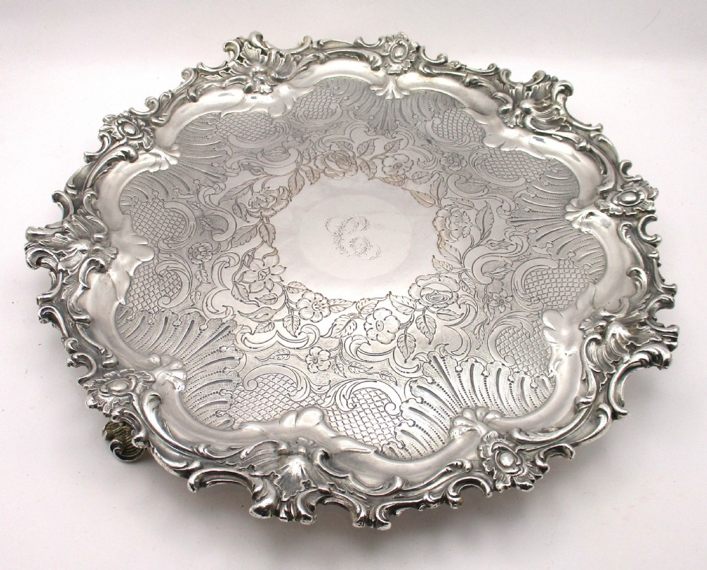 A circular Victorian Sheffield silver-plated serving tray featuring an ornate Rococo scroll border and intricate floral engraving across the flat surface. View II