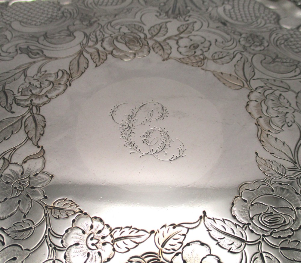 A circular Victorian Sheffield silver-plated serving tray featuring an ornate Rococo scroll border and intricate floral engraving across the flat surface. View IV