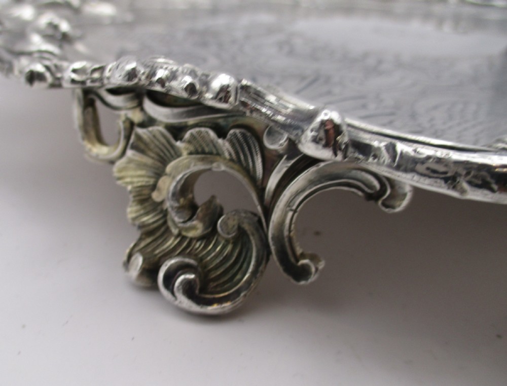 A circular Victorian Sheffield silver-plated serving tray featuring an ornate Rococo scroll border and intricate floral engraving across the flat surface. View VII