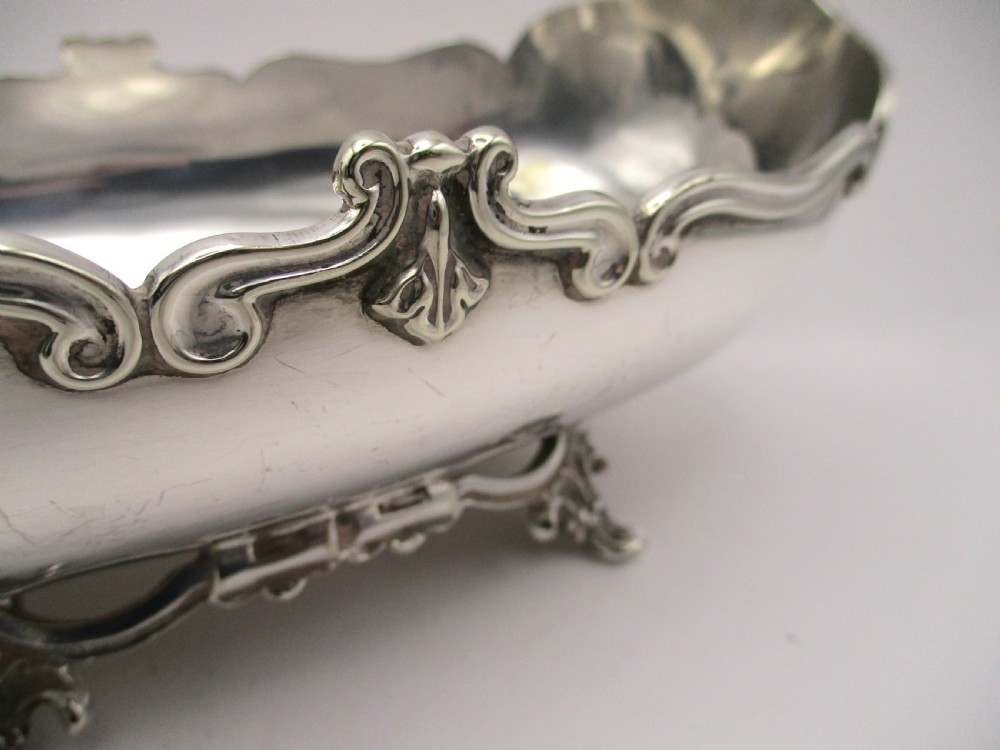 An Art Nouveau silver-plated boat-shaped bonbon dish featuring curved side handles, a decorative scrolled rim, and four cast scroll feet. View III