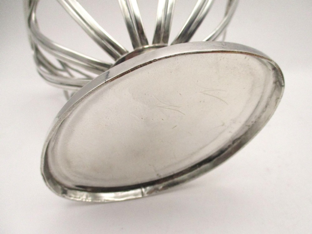 A Georgian Sheffield plated silver wirework sugar basket featuring an oval engraved cartouche, overhead handle, pedestal foot, and cobalt blue glass liner. View XI
