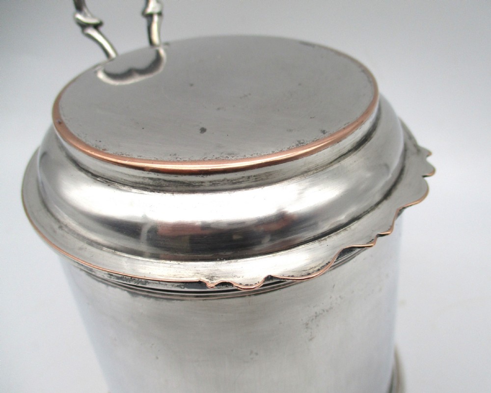 A late 18th-century silver-plated pint tankard featuring a hinged stepped lid, thumbpiece lever, curved scroll handle, and subtle copper exposure along worn rim edges. View VIII