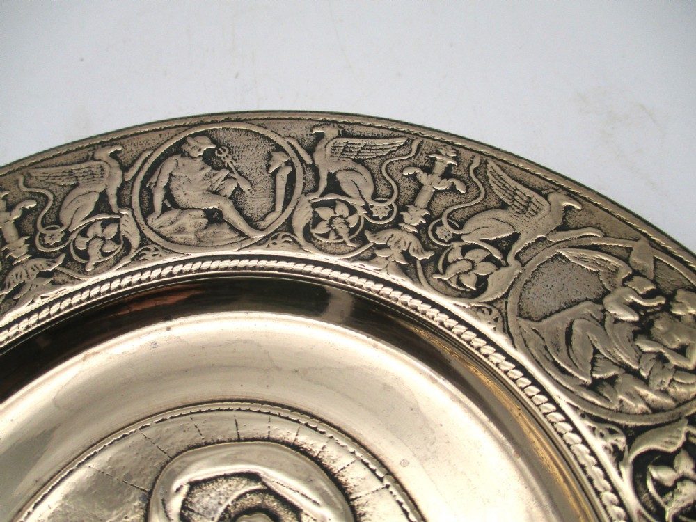 A circular 19th-century bronze platter featuring a central relief of a classical chariot and an ornate outer rim detailed with mythological figures and grotesques. View VI