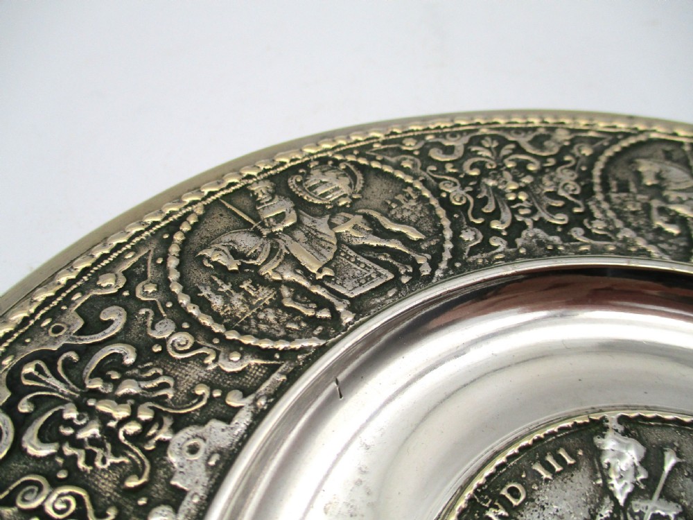 A circular 19th-century silver-plated bronze platter featuring a central relief profile of Emperor Ferdinand III on horseback surrounded by detailed equestrian vignettes and ornate scrolling foliage. View V