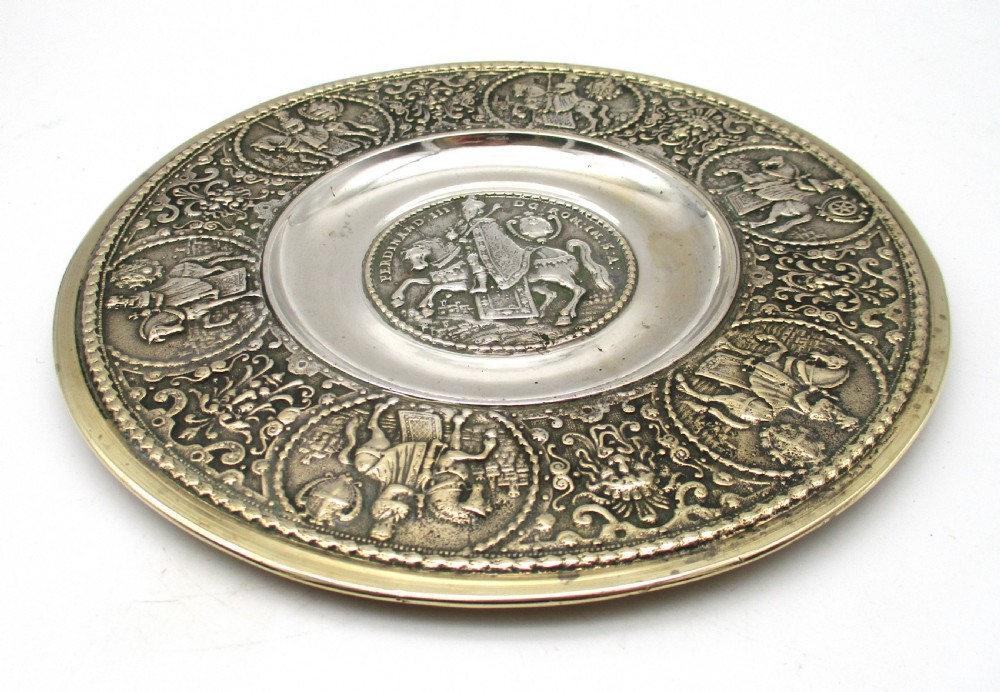 A circular 19th-century silver-plated bronze platter featuring a central relief profile of Emperor Ferdinand III on horseback surrounded by detailed equestrian vignettes and ornate scrolling foliage. View VII