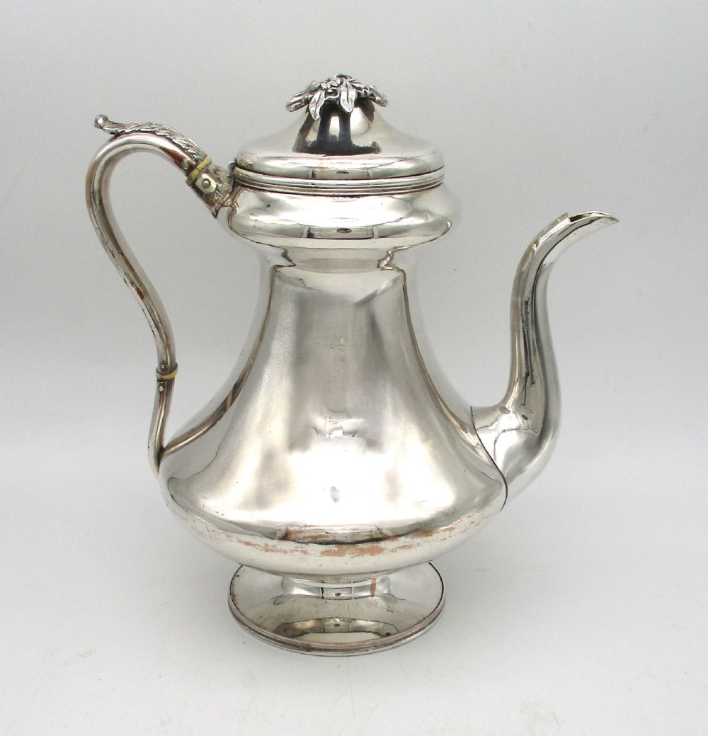 A Regency period Old Sheffield plated silver coffee pot featuring a baluster-shaped body, goose-neck spout, foliate finial, and scroll handle with heat insulators. View VI