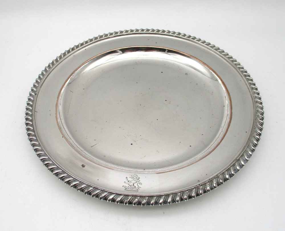 A circular Georgian Old Sheffield silver-plated dinner plate featuring a gadrooned rope-twist rim and an engraved armorial crest on the edge. View II