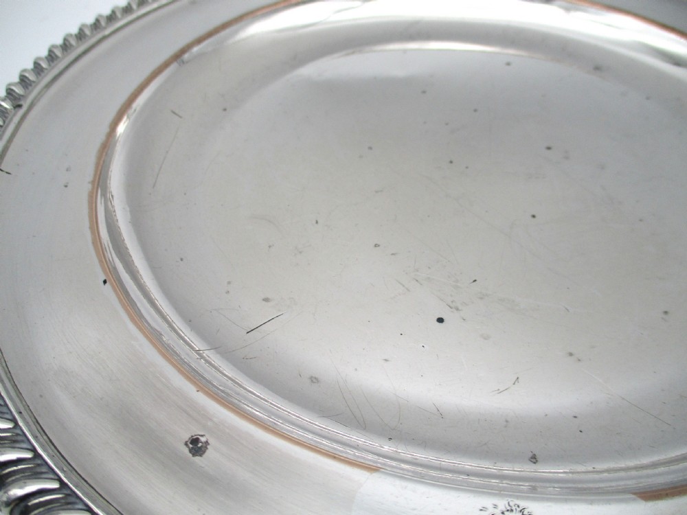 A circular Georgian Old Sheffield silver-plated dinner plate featuring a gadrooned rope-twist rim and an engraved armorial crest on the edge. View IV
