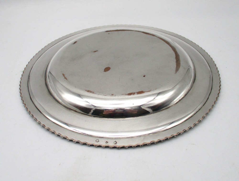 A circular Georgian Old Sheffield silver-plated dinner plate featuring a gadrooned rope-twist rim and an engraved armorial crest on the edge. View VII