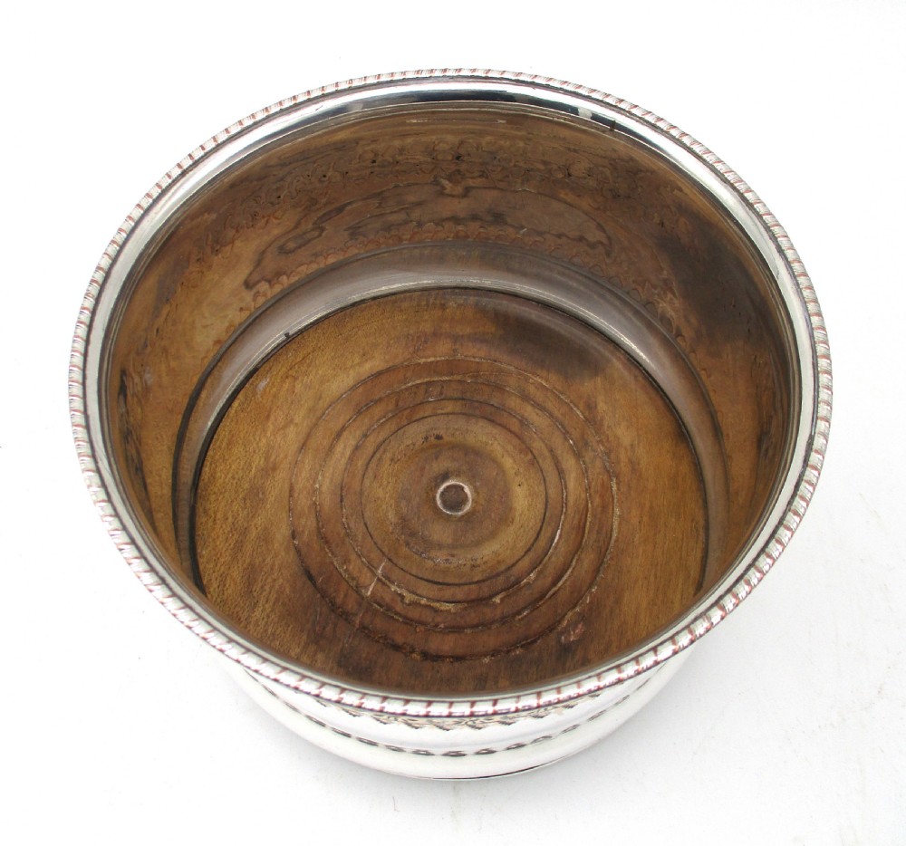 A pair of deep, circular silver-plated wine coasters featuring pierced floral decorative bands, beaded rims, and inset wooden bases. View III