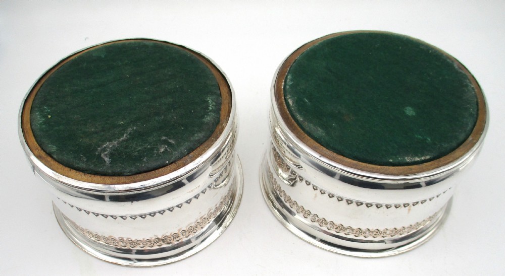 A pair of deep, circular silver-plated wine coasters featuring pierced floral decorative bands, beaded rims, and inset wooden bases. View VI