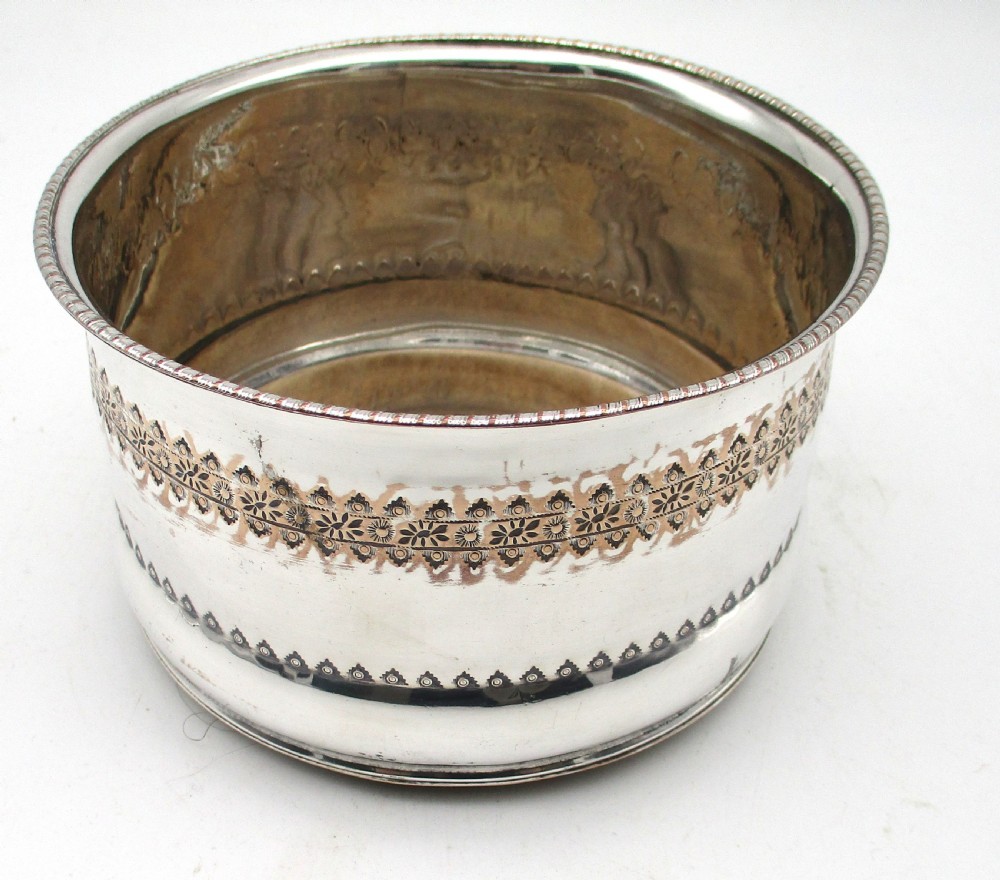 A pair of deep, circular silver-plated wine coasters featuring pierced floral decorative bands, beaded rims, and inset wooden bases. View VII
