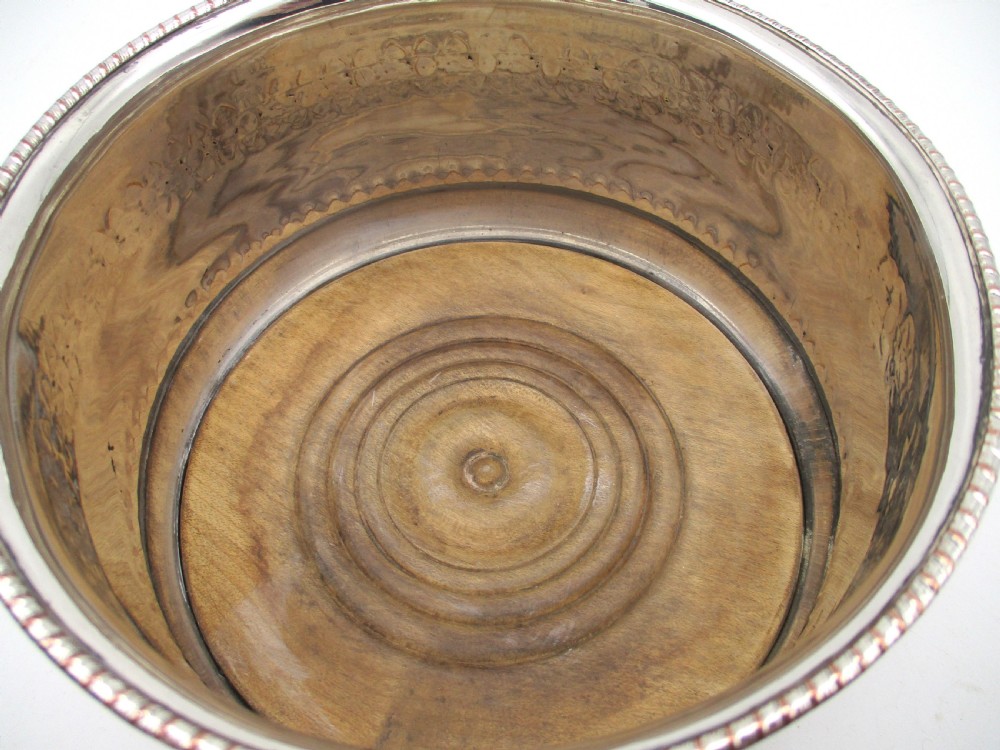 A pair of deep, circular silver-plated wine coasters featuring pierced floral decorative bands, beaded rims, and inset wooden bases. View IX