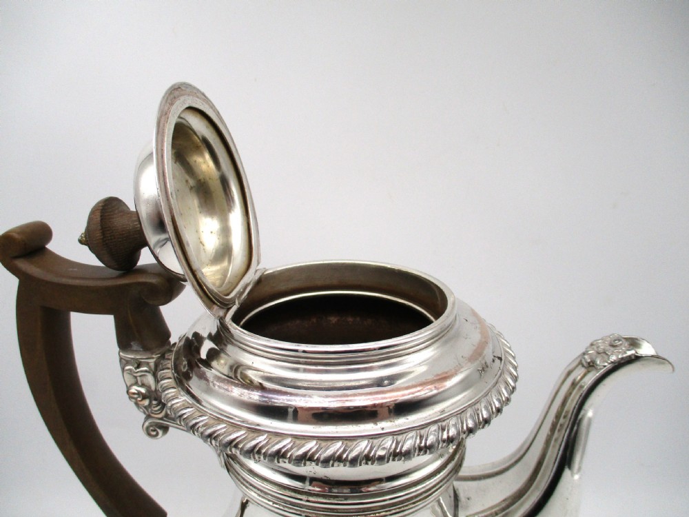 An antique Regency silver-plated coffee pot featuring a carved wooden handle, a gadrooned rim, and a stepped circular base. View V
