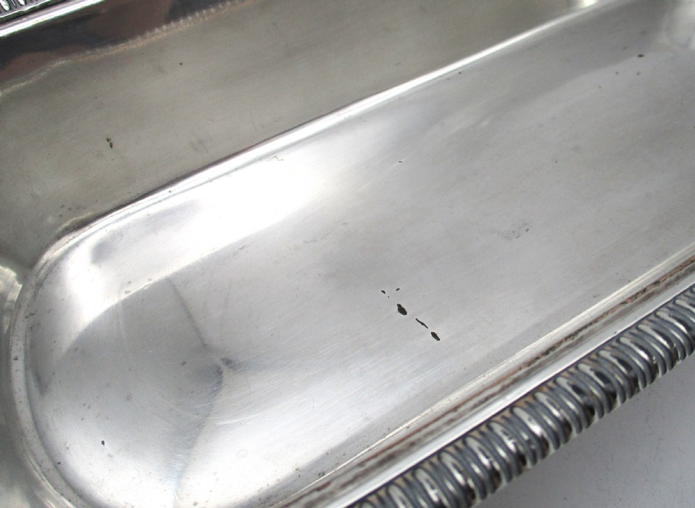 An oblong silver-plated knife tray featuring a gadrooned rim and a smooth polished interior well. View III