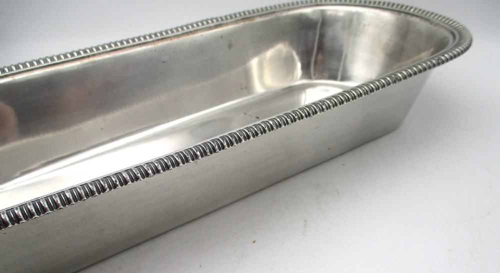 An oblong silver-plated knife tray featuring a gadrooned rim and a smooth polished interior well. View VI