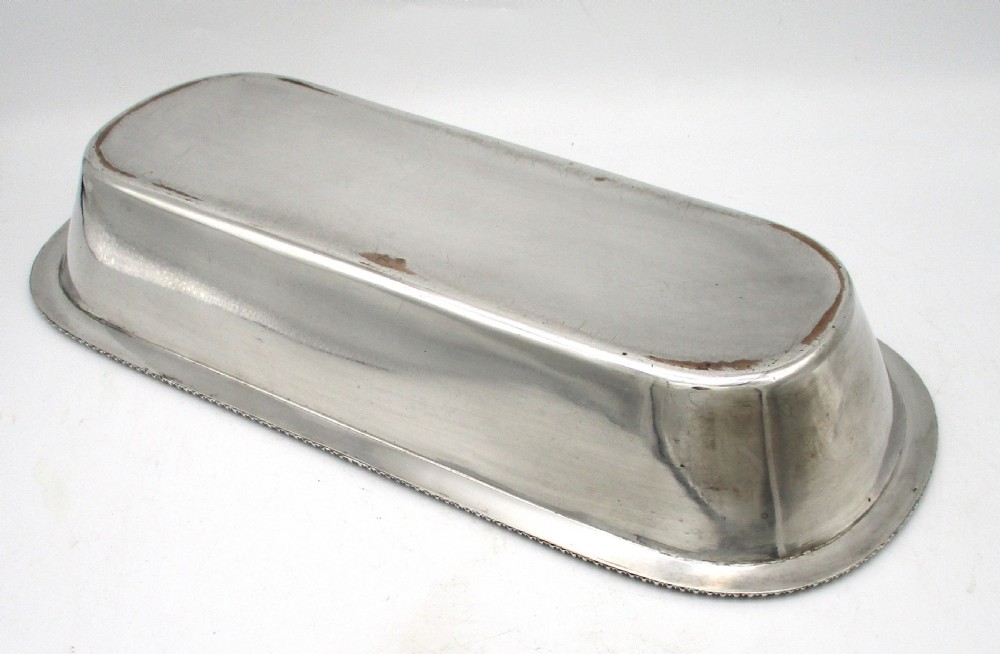 An oblong silver-plated knife tray featuring a gadrooned rim and a smooth polished interior well. View VIII