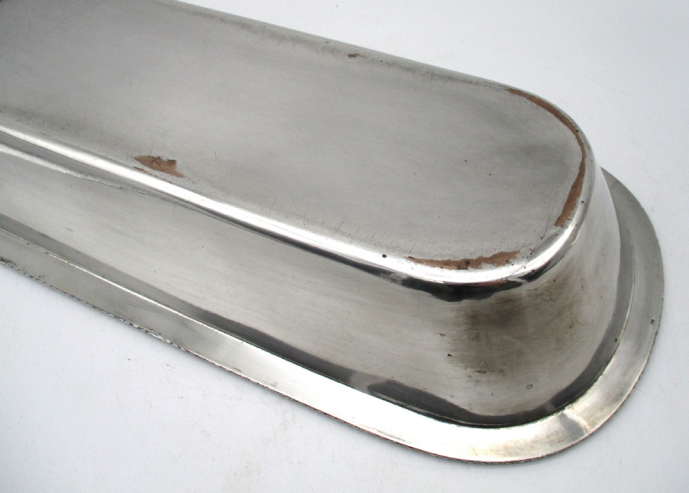 An oblong silver-plated knife tray featuring a gadrooned rim and a smooth polished interior well. View IX
