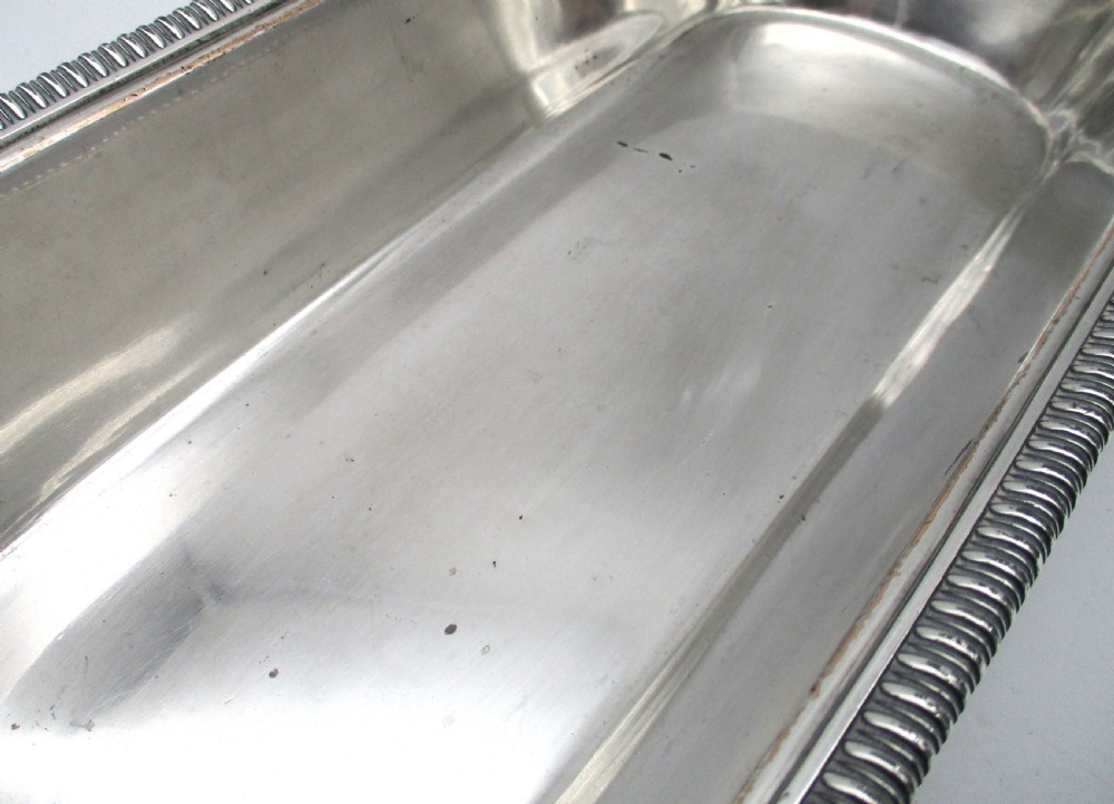 An oblong silver-plated knife tray featuring a gadrooned rim and a smooth polished interior well. View XI