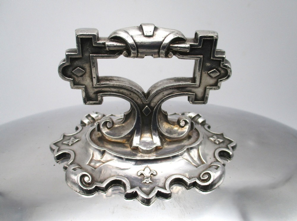 An oval Old Sheffield Plated meat dome featuring a moulded rim, an engraved crest, and a cast scrolling handle. View III